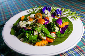 Stir fried mixed vegetables served on fresh banana leaves decorated with beautiful orchid flowers. Carrot 
kale tomato 
green peas 
Broccoli 
cauliflower 
baby corn 
purple cabbage banana leaves