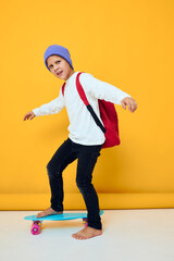 Fototapeta na wymiar happy schoolboy rides a skateboard in a blue hat isolated background