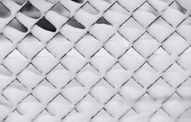 Lattice steel fence during snowfall