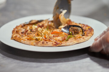 Cutting Hot seashell pizza shrimp and tomatoes close up