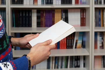 male student holding a book in the library