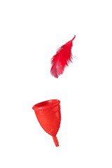 Red silicone menstrual cup with water drops and  levitating feather  on a white background. Women's health concept, zero waste. Isolated