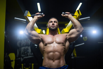 Front view close up of a very strong and muscular athlete doing exercises in hammer strength...