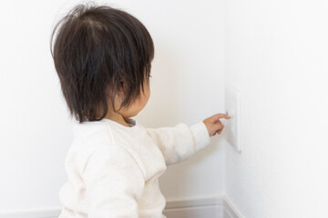 壁のコンセントに指を伸ばしている赤ちゃん(1歳5か月、女の子、日本人）