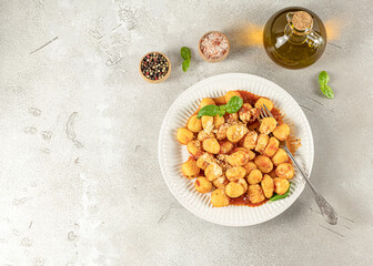 Homemade recipe potato gnocchi with tomato sauce and cheese on a white plate.