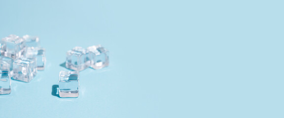 transparent ice cubes on a blue background. Top view, flat lay. Banner