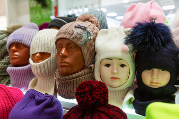 Knitted warm hats on the heads of mannequins in a shop window. Fashion in the cold season. Close-up.