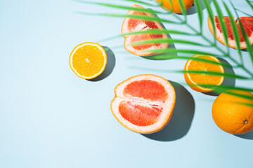 citrus fruits, oranges, grapefruit and palm leaf on a blue background. Top view, flat lay