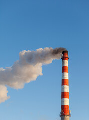 White thick smoke from the boiler room chimney. Smoke against the blue sky. Air pollution. Heating of the city. Industrial zone.