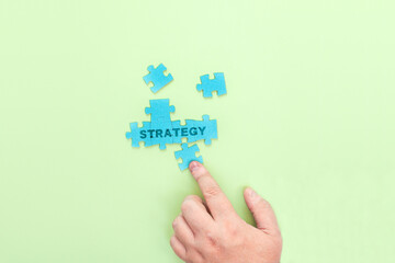 Businessman connecting puzzle pieces with the word Strategy
