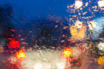 Fototapeta na wymiar Blurry car silhouette seen through water drops on the car windshield