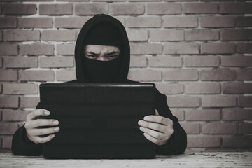 Anonymous hacker using laptop for stealing personal data from internet.