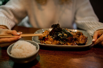 unrecognizable woman holds chopsticks while devouring spicy vegetables in Asian restaurant.