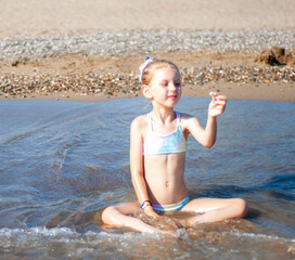 Little girl playing on the beach by the sea