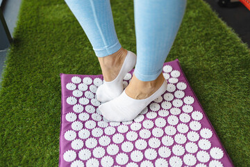 Female feet standing on acupressure mat. Alternative medicine massage concept