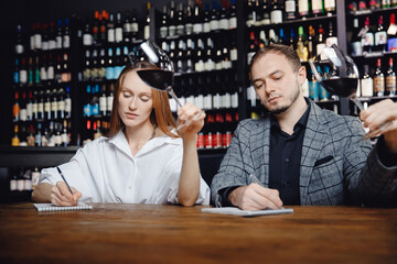 Tasting red wine Professional sommeliers two man and woman and taking notes at degustation notepad
