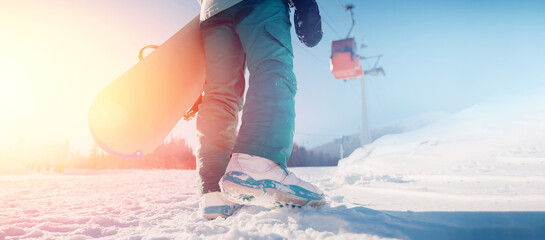 Fototapeta Back woman snowboarder stands with snowboard sun light, banner winter ski resort obraz