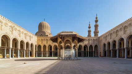 Ablution fountain mediating the courtyard of public historic mosque of Sultan al Muayyad, with background of arched corridors surrounding the courtyard, dome and minarets of the mosque, Cairo, Egypt