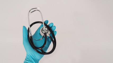 Hand with a stethoscope. Hand wears the blue medical glove and a long-sleeve gown on white background.