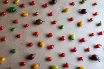Red yellow brown cherry tomatoes are scattered on a gray background, upper view. Colorful cherry tomatoes for publication, poster, screensaver, wallpaper, postcard, banner, cover, post. Healthy diet