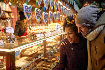A young couple enjoying a christmas market while walking the city. Christmas, New Year, holiday,...