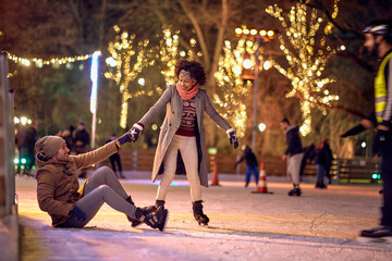 Lovely multiethnic couple enjoying ice skating; Christmas joy concept - obrazy, fototapety, plakaty