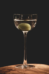 Close up shot of a beautiful, elegant martini cocktail with olive in a tall, vintage pony glass, isolated on black background. Dark, moody, adult atmosphere.