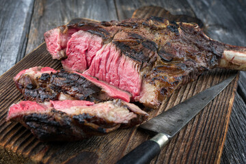 Traditional barbecue wagyu tomahawk beef steak sliced and served as close-up on a rustic wooden board