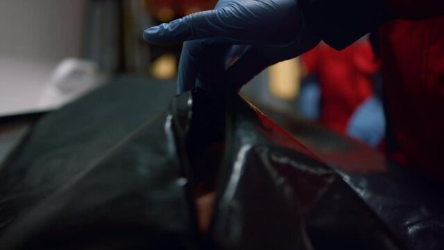 Closeup paramedic hands closing body bag with dead man after coronavirus disease