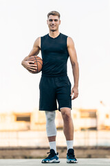 Vertical portrait of a tall man with a basketball outdoors