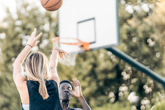 Selective Focus On A Woman Shooting A Ball At The Basket While A Man Defends It