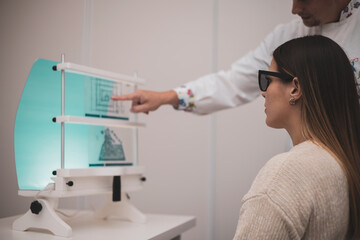 Naklejka premium a beautiful young woman undergoes vision therapy in an optician with a professional.