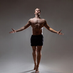 A young muscular man in an expressive pose, pretentious pose of the hero with outstretched arms....