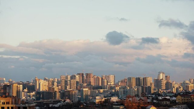 Time Lapse shot of city with sunlight and clouds floating in sky over buildings