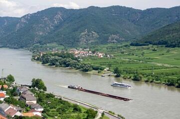 Landscape with ferry ship and heavy freight vessel on a Danube river in Austria near Spitz