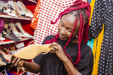 Black beautiful Nigerian girl with rasta red hair holding shoes at the BOUTIQUE