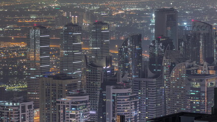 Jumeirah Lakes Towers district with many skyscrapers along Sheikh Zayed Road aerial night timelapse.