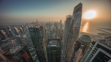Skyline sunset view of Dubai Marina showing canal surrounded by skyscrapers along shoreline day to night timelapse. DUBAI, UAE