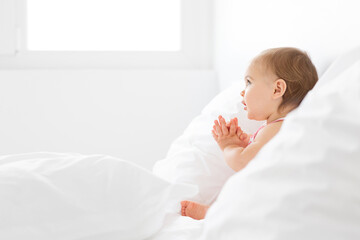 Profile portrait of baby girl with folded hands as if praying