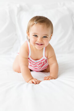 cute smiling baby girl crawling on white bed