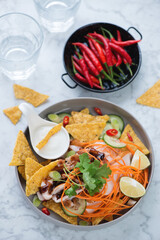 Plate with chili chicken nachos over light-grey marble background, vertical shot, elevated view