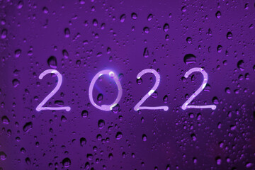 New Year 2022 on a wet glass background. Concept light