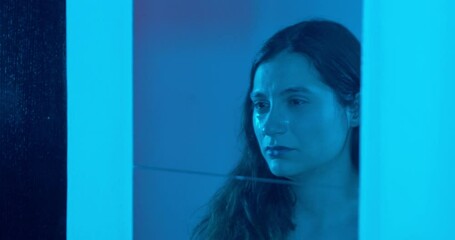 young sad woman in front of the mirror stares at her image crying
