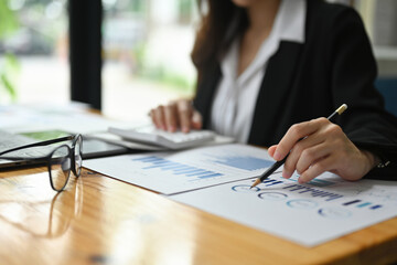 Close-up image of an insurance agent working at the wooden working desk surrounded by a computer...