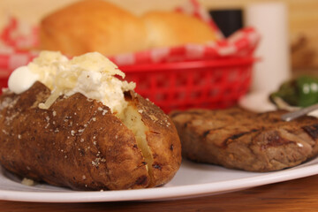 Baked Potato With Cheese and Butter Rolls and Jalapeno peppers in background