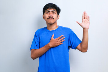 Young handsome asian man smiling swearing with hand on chest and fingers up, making a loyalty...
