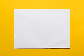 Frame of a sheet of white paper on a yellow background. Copy space. Top view. 
