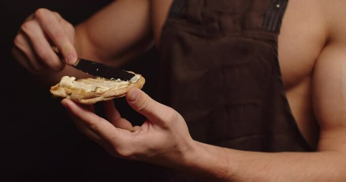Young sexy man seductively spreads butter on bread