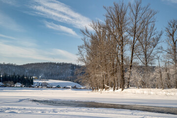 Not completely frozen body of water. Ice and water create a geometric pattern. On the other side is the village and the mountains.