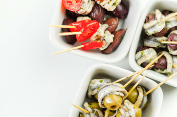 The traditional Spanish appetizers of olives, tomatoes and anchovies in a white ceramic bowls
